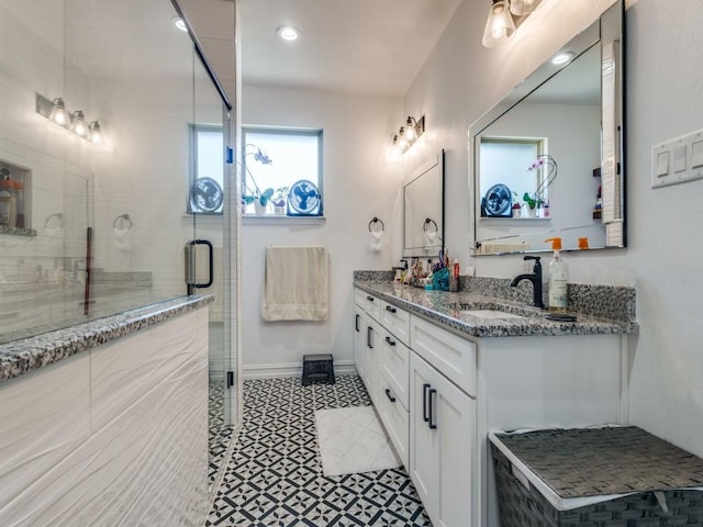 full bathroom with baseboards, double vanity, a sink, and a shower stall