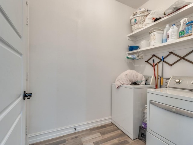 washroom featuring laundry area, baseboards, light wood-style flooring, and washing machine and clothes dryer