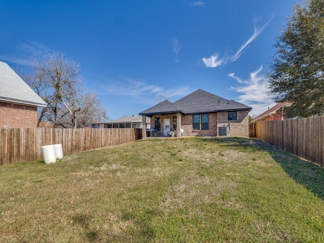 rear view of house with brick siding, a fenced backyard, central AC unit, and a yard