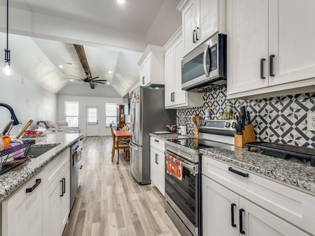 kitchen featuring stainless steel appliances, white cabinets, open floor plan, light wood finished floors, and tasteful backsplash