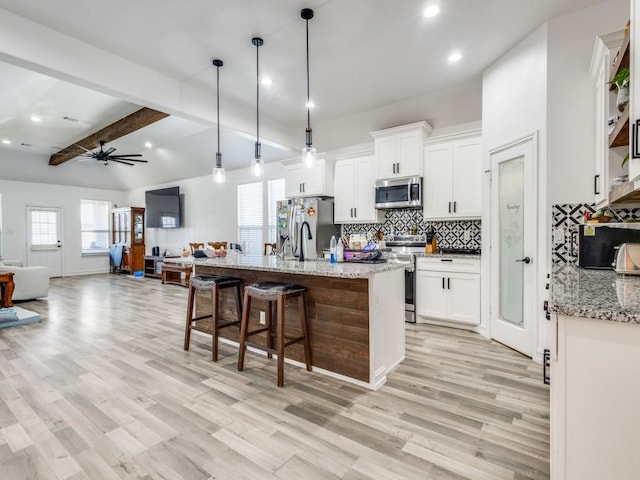 kitchen featuring open floor plan, stainless steel appliances, light wood-style floors, and white cabinets