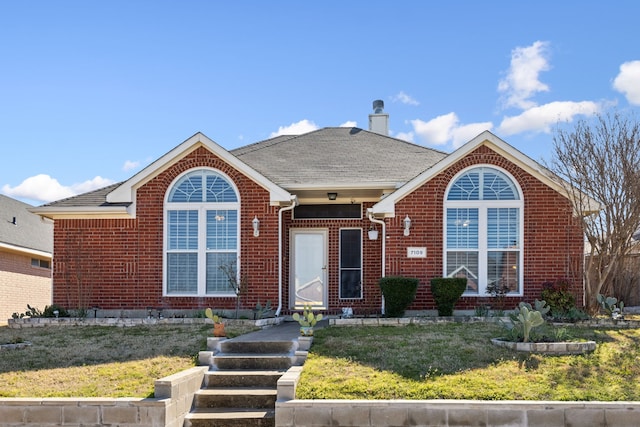 ranch-style home featuring roof with shingles, brick siding, a front lawn, and a chimney