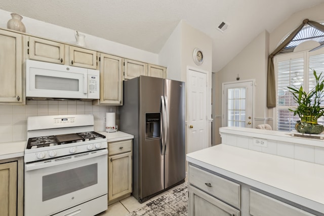 kitchen with white appliances, visible vents, decorative backsplash, vaulted ceiling, and light countertops