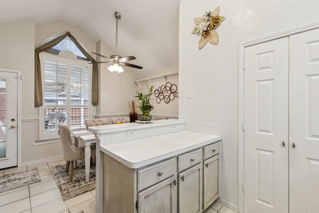 kitchen featuring light tile patterned floors, lofted ceiling, light countertops, ceiling fan, and a peninsula