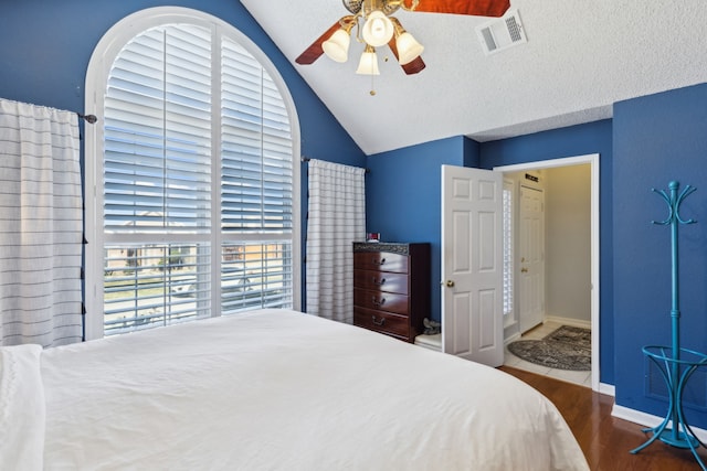 bedroom featuring a textured ceiling, lofted ceiling, wood finished floors, visible vents, and baseboards