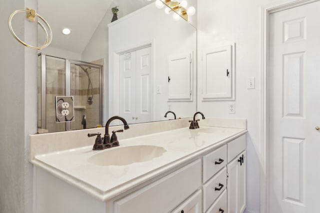 bathroom with a stall shower, vaulted ceiling, a sink, and double vanity