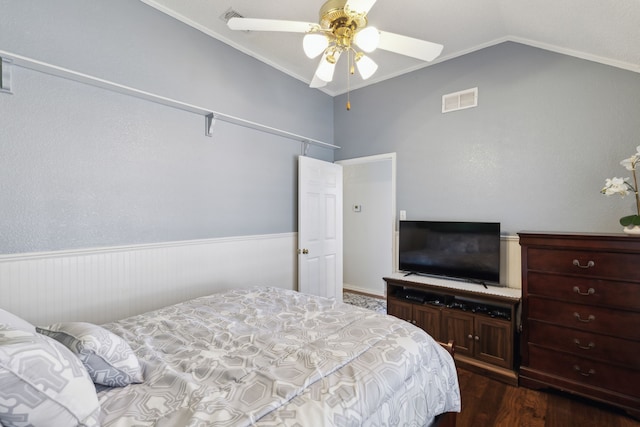 bedroom featuring ceiling fan, a wainscoted wall, dark wood-style flooring, visible vents, and vaulted ceiling