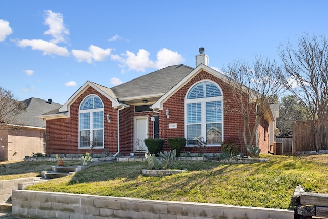 ranch-style home with a front yard, a chimney, and brick siding