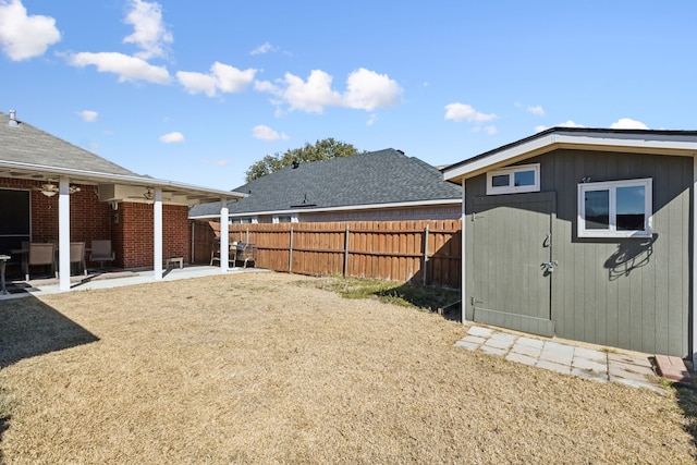 view of yard with a shed, fence, a patio, and an outbuilding