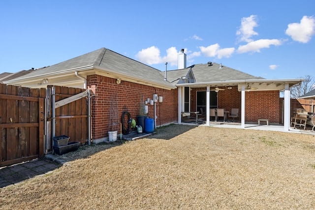 back of house featuring brick siding, a patio, a chimney, a ceiling fan, and fence