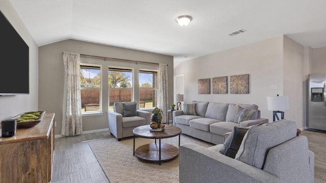 living room with lofted ceiling, baseboards, visible vents, and wood finished floors