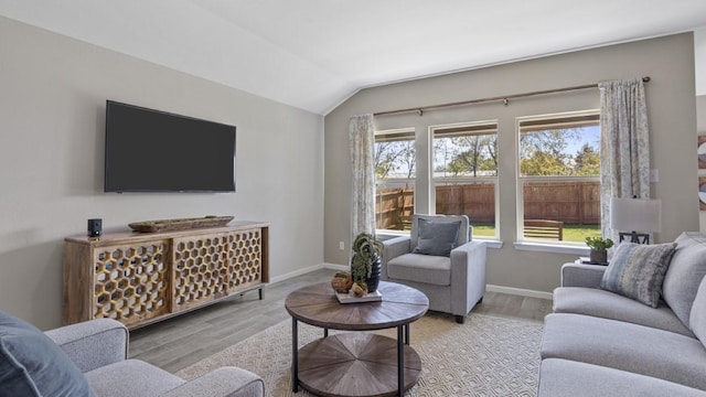 living area with vaulted ceiling, baseboards, and wood finished floors