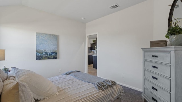 bedroom with lofted ceiling, baseboards, visible vents, and dark colored carpet