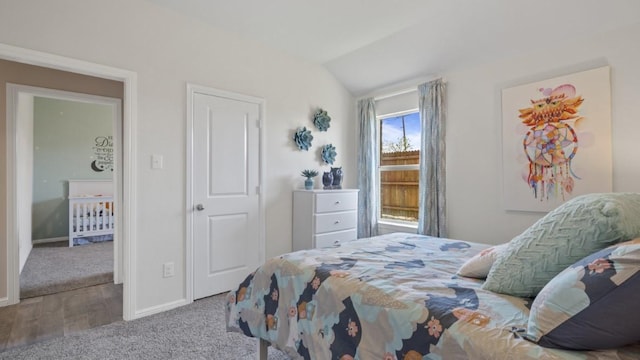 carpeted bedroom with lofted ceiling and baseboards