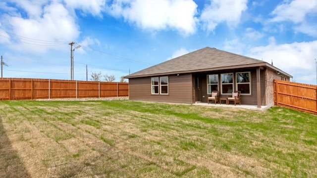 back of property with a fenced backyard, a lawn, and a patio