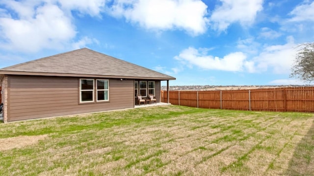 rear view of house with fence, a patio, and a lawn