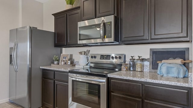 kitchen with light stone counters, stainless steel appliances, and dark brown cabinets