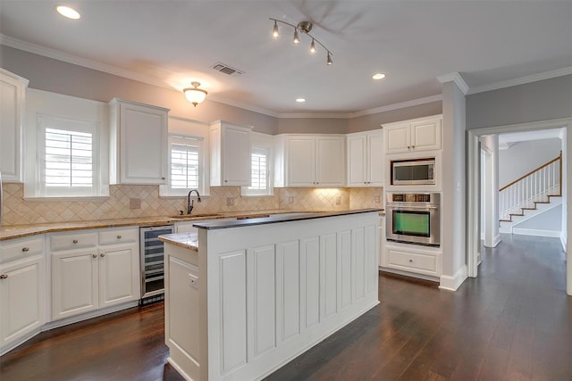 kitchen featuring wine cooler, stainless steel appliances, a sink, ornamental molding, and dark wood finished floors