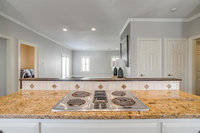 kitchen with ornamental molding, washing machine and dryer, white cabinets, and stainless steel electric stovetop