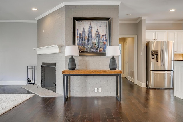 unfurnished living room with a brick fireplace, ornamental molding, and wood finished floors