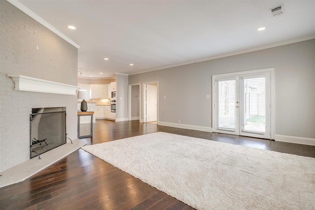 unfurnished living room featuring crown molding, a fireplace, dark wood finished floors, and baseboards