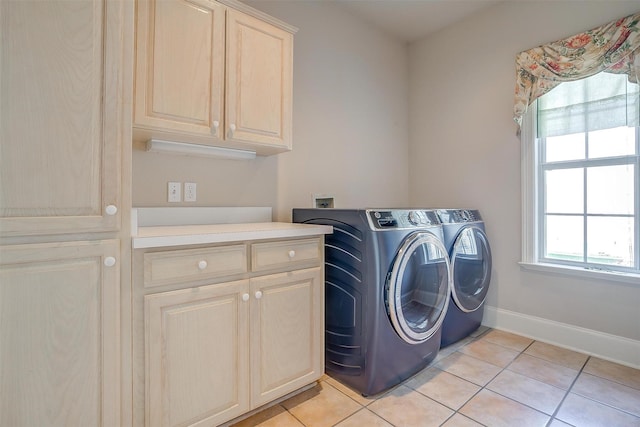 laundry area featuring light tile patterned floors, washing machine and clothes dryer, cabinet space, and baseboards