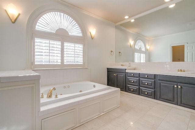 bathroom with ornamental molding, plenty of natural light, a tub with jets, and double vanity