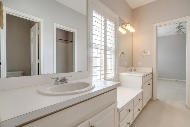 bathroom with two vanities, a sink, toilet, and ceiling fan