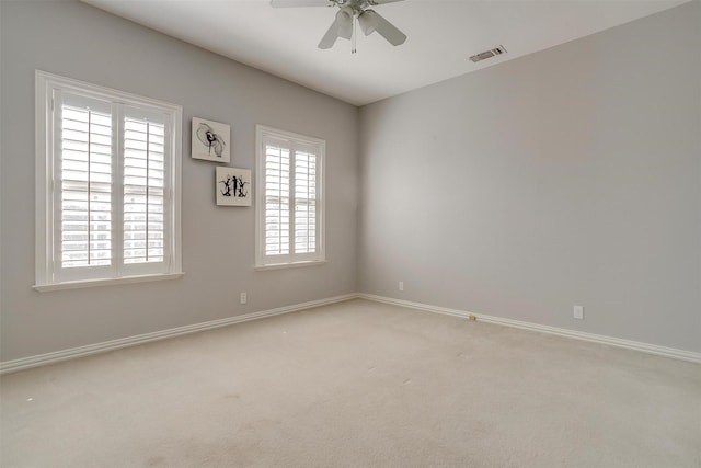 carpeted spare room featuring a ceiling fan, visible vents, and baseboards