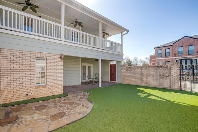 rear view of house featuring french doors, brick siding, a ceiling fan, a patio area, and fence