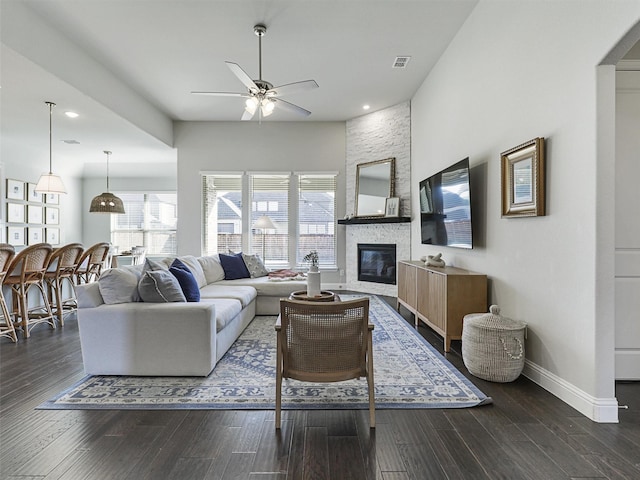 living room featuring visible vents, baseboards, a ceiling fan, wood finished floors, and a fireplace