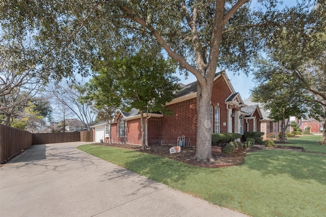 view of property exterior featuring brick siding, a yard, fence, a garage, and driveway