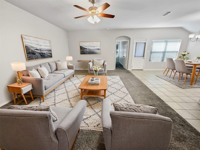 living area featuring arched walkways, lofted ceiling, tile patterned flooring, ceiling fan with notable chandelier, and visible vents