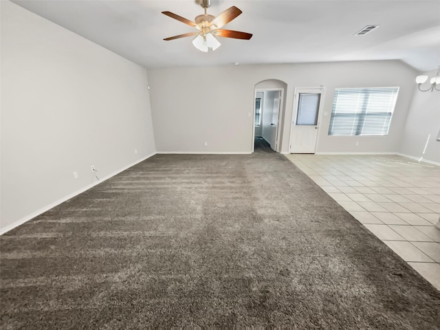 unfurnished living room with arched walkways, carpet, visible vents, ceiling fan, and tile patterned floors