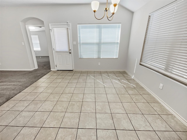 empty room featuring baseboards, arched walkways, a chandelier, and light colored carpet