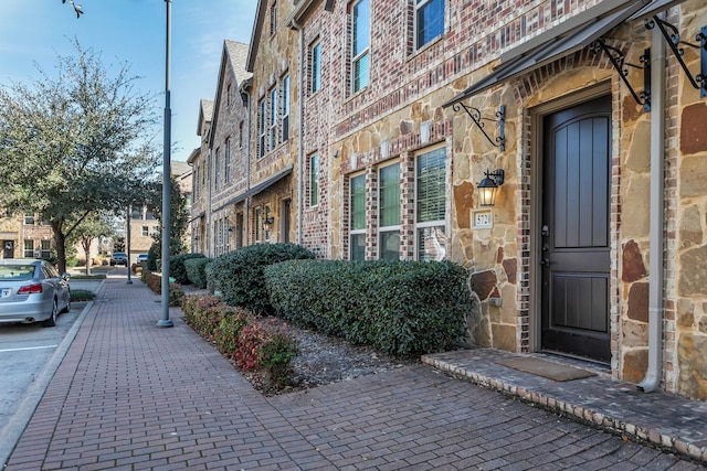 entrance to property featuring stone siding and brick siding