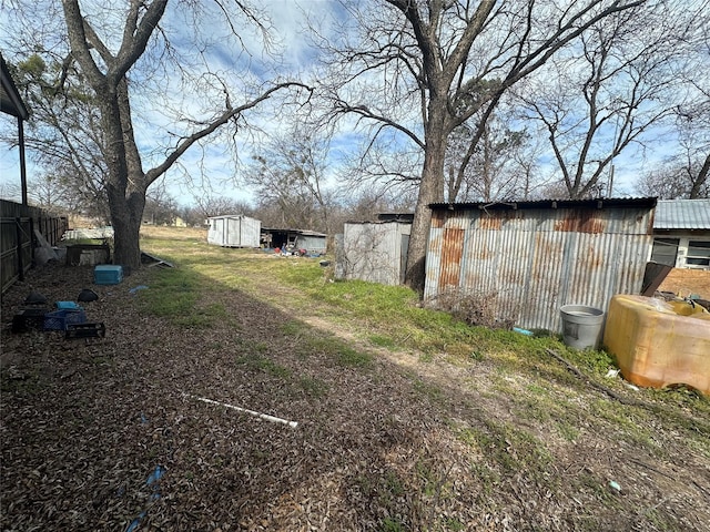 view of yard featuring a shed, fence, and an outbuilding