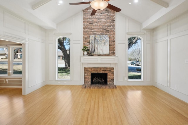 unfurnished living room featuring a fireplace, wood finished floors, a ceiling fan, and a decorative wall