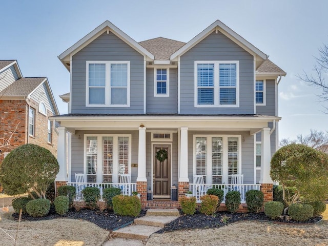 craftsman inspired home with covered porch and roof with shingles