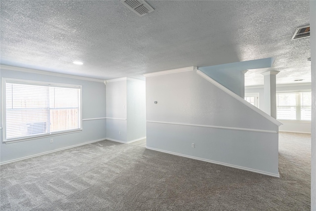 unfurnished room featuring a wealth of natural light, visible vents, and carpet flooring