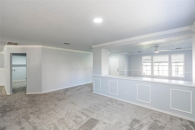 spare room with a textured ceiling, ornamental molding, carpet flooring, and visible vents