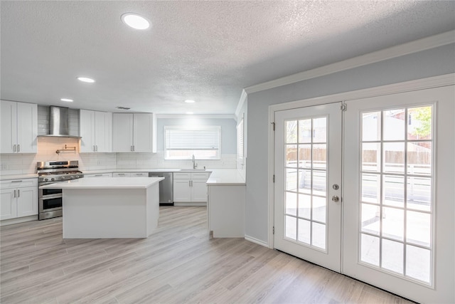 6512 Willow Oak Ct, Fort Worth, TX 76112 - kitchen with a textured ceiling, wall chimney exhaust hood, a sink, appliances with stainless steel finishes, and backsplash