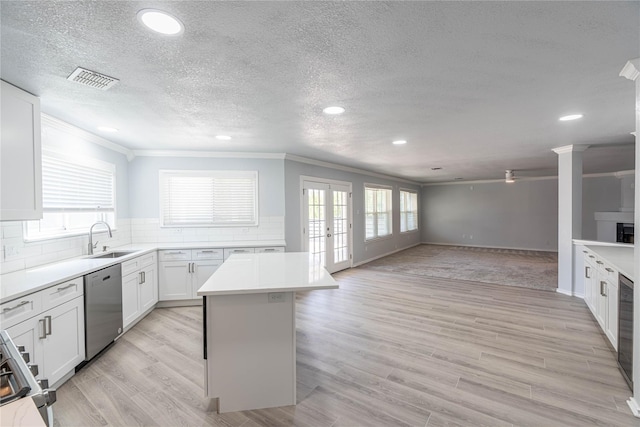 kitchen with a healthy amount of sunlight, a sink, light wood finished floors, and stainless steel dishwasher