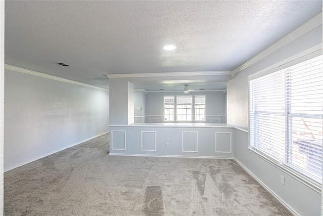 carpeted spare room featuring ornamental molding, visible vents, a textured ceiling, and baseboards