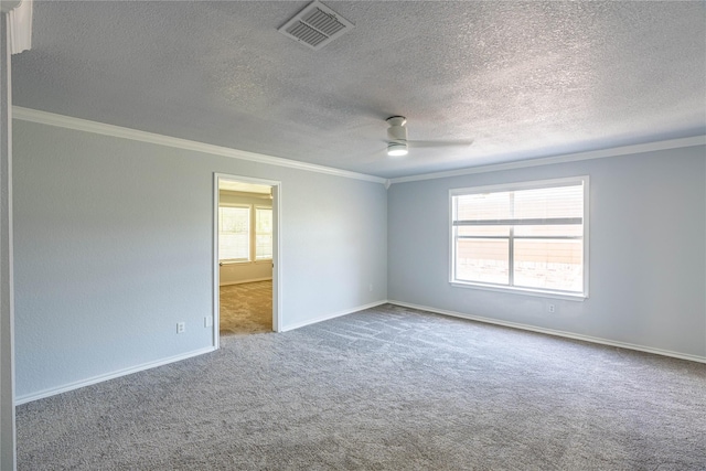 empty room with carpet floors, plenty of natural light, visible vents, and crown molding