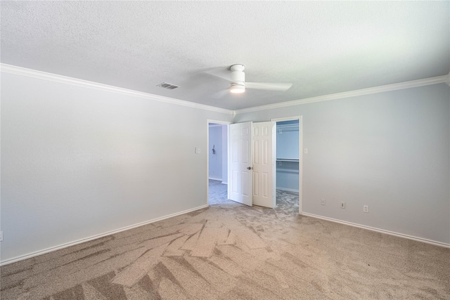 carpeted empty room featuring visible vents, ornamental molding, ceiling fan, a textured ceiling, and baseboards