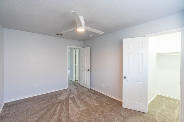 unfurnished bedroom featuring a textured ceiling, ceiling fan, carpet flooring, visible vents, and baseboards