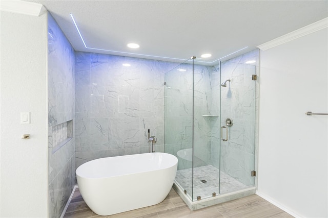 bathroom featuring a freestanding tub, wood tiled floor, a marble finish shower, and crown molding