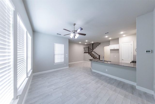 kitchen featuring stone counters, visible vents, white cabinets, baseboards, and light wood finished floors