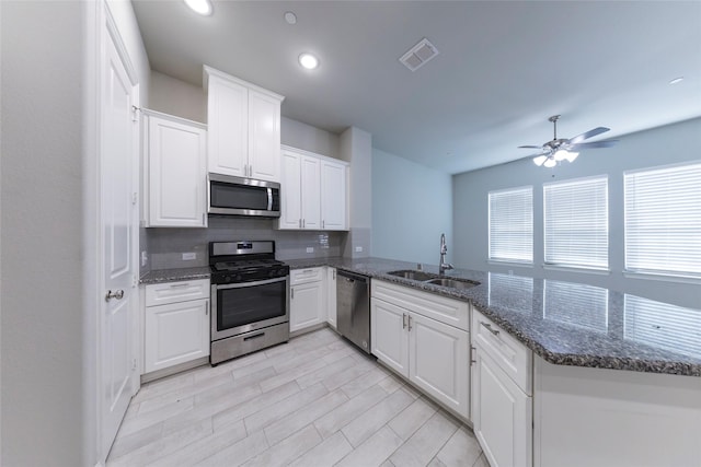 kitchen with visible vents, white cabinets, appliances with stainless steel finishes, a peninsula, and a sink